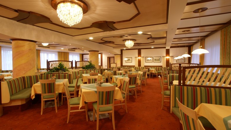 Elegant dining room with chandeliers and striped upholstered furniture.