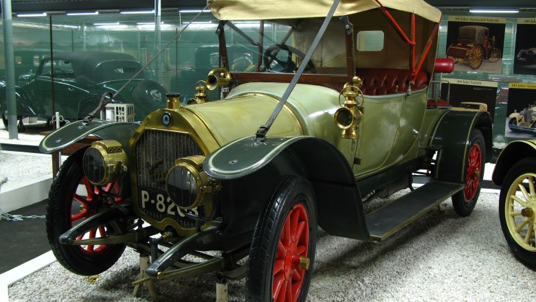 Ein Oldtimer mit rotem Verdeck und roten Rädern in einem Automobilmuseum.