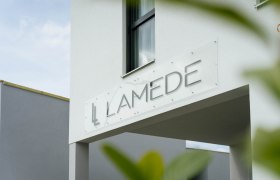 Moderne Gebäudeaußenansicht mit dem Schriftzug 'LAMEDE' auf einem Schild.