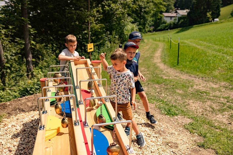 Kinder spielen an einer Kugelbahn im Freien.