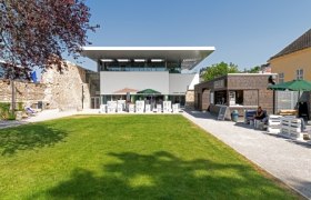 Modern building complex with garden and outdoor seating area.