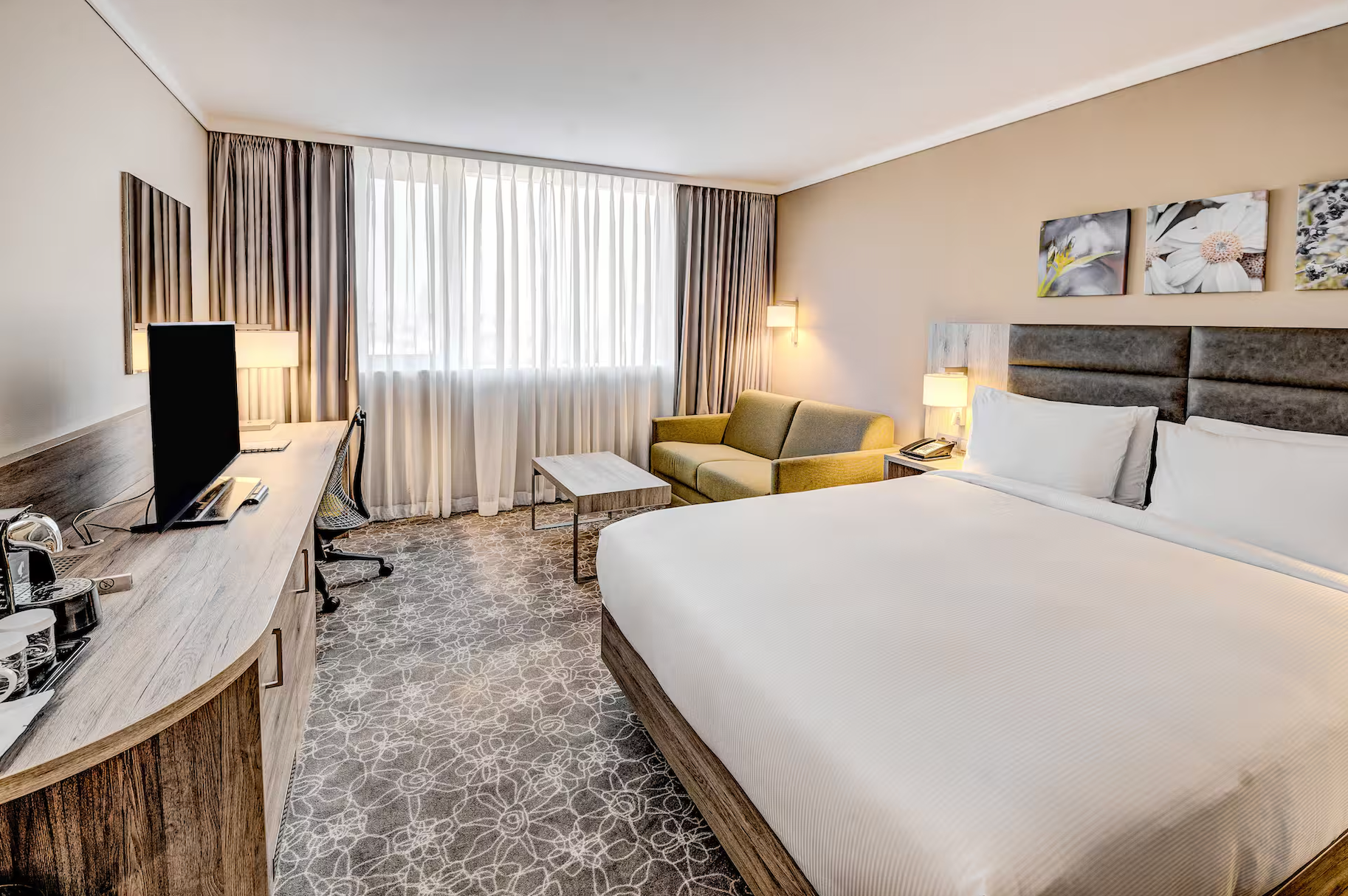 Großes Doppelzimmer mit Teppichboden, Sitzmöglichkeiten, Schreibtisch und hellen Farben.
