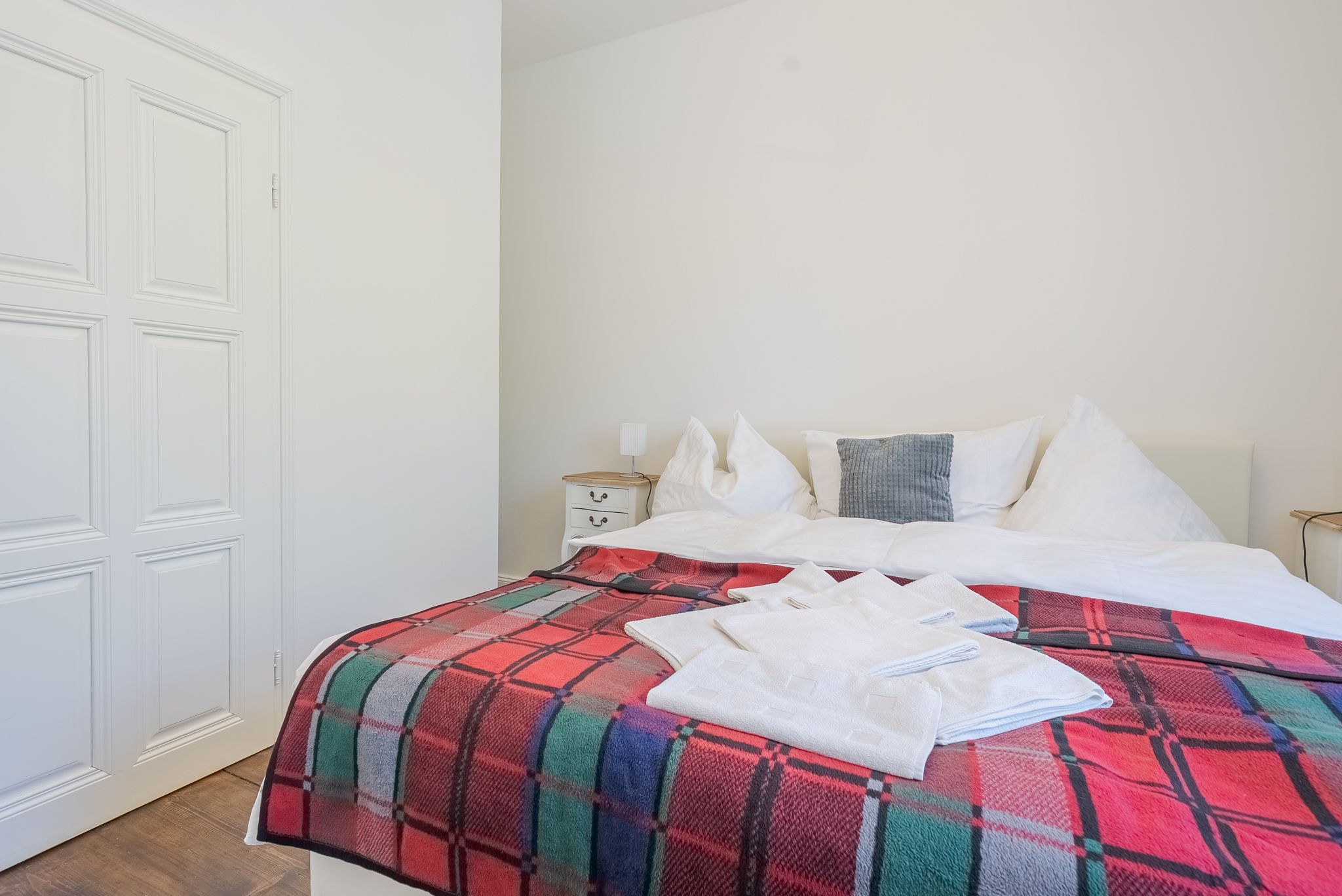 Ein gemütliches Schlafzimmer mit einem Doppelbett, das mit einer karierten Decke und weißen Handtüchern dekoriert ist.