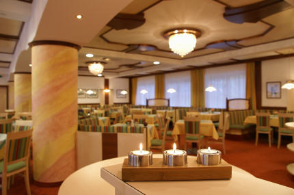 Ein eleganter Hotel-Saal mit gedeckten Tischen, Kronleuchtern und Kerzen auf einem Tisch im Vordergrund.