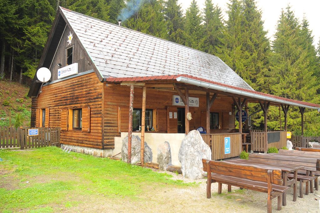 bewirtschaftet Holzhütte am Preiner Gscheid, davor ein Dachvorsprung und Holztische und Bänke