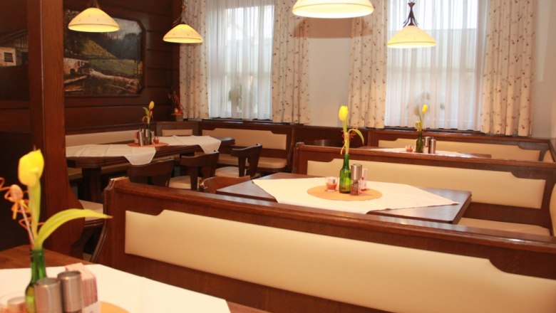 Gemütliches Stüberl mit Holzmöbeln, Tischdekoration und Lampen.