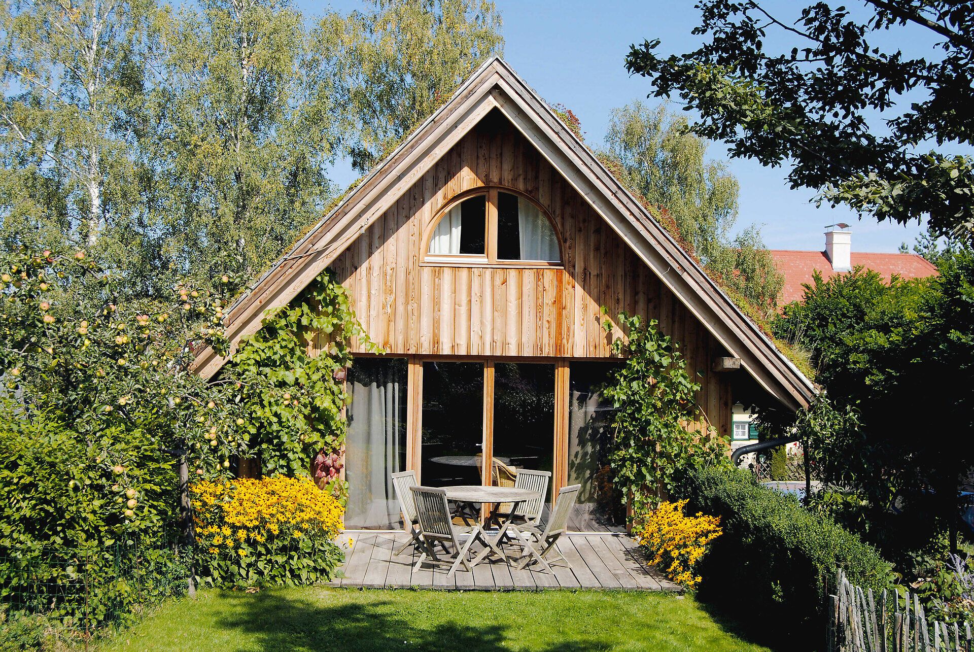 Umgeben von üppigem Grün und bunten Blumen, strahlt das Ferienhaus eine einladende Gemütlichkeit aus. Die Holzverkleidung und die große Terrasse laden dazu ein, die frische Bergluft zu genießen und die Ruhe der Natur zu erleben.