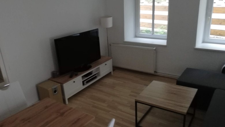 Modernes Wohnzimmer mit Fernseher, Sofa und Holztisch.
