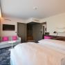 Moderne Hotelsuite mit Doppelbett, Sofa, Fernseher und Schreibtisch.
