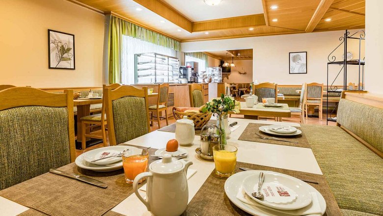 Ein gemütlicher Frühstücksraum mit gedeckten Tischen, Saftgläsern und Kaffeekannen.