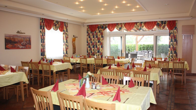 An elegant restaurant with laid tables and red napkins.