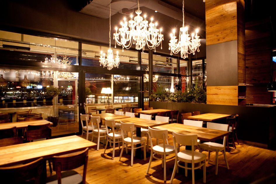 Innenansicht eines stilvollen Restaurants mit Kronleuchtern und Holzmöbeln.