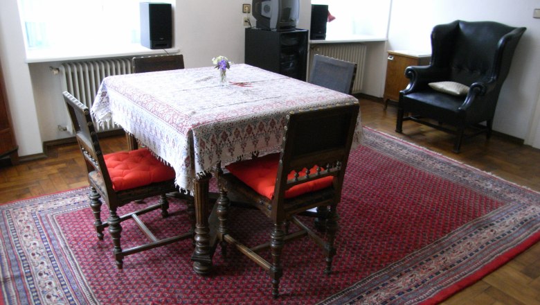 Wohnzimmer mit Tisch, Stühlen und Teppich.