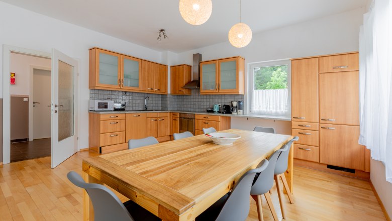 Moderne Küche mit Holzmöbeln und großem Esstisch.