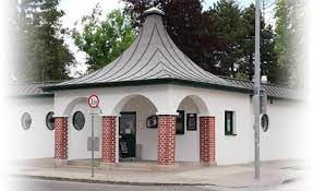 Kleines Gebäude mit rundem Dach und roten Backsteinpfeilern.