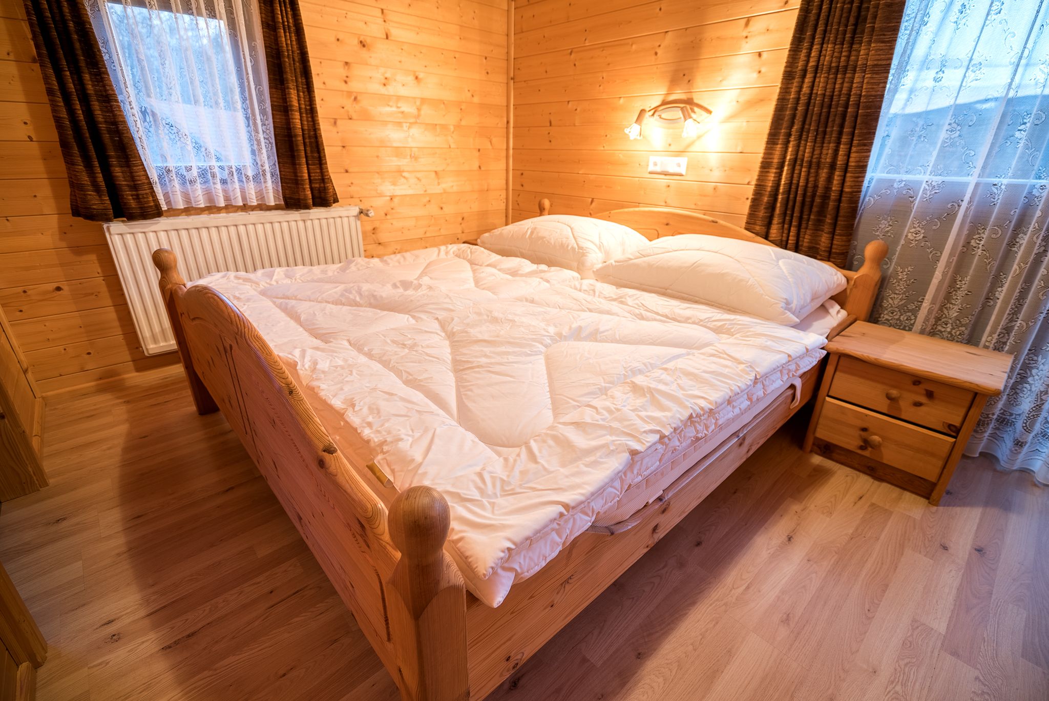 Gemütliches Schlafzimmer mit Holzwänden, Doppelbett und Nachttisch in einer Ferienwohnung.