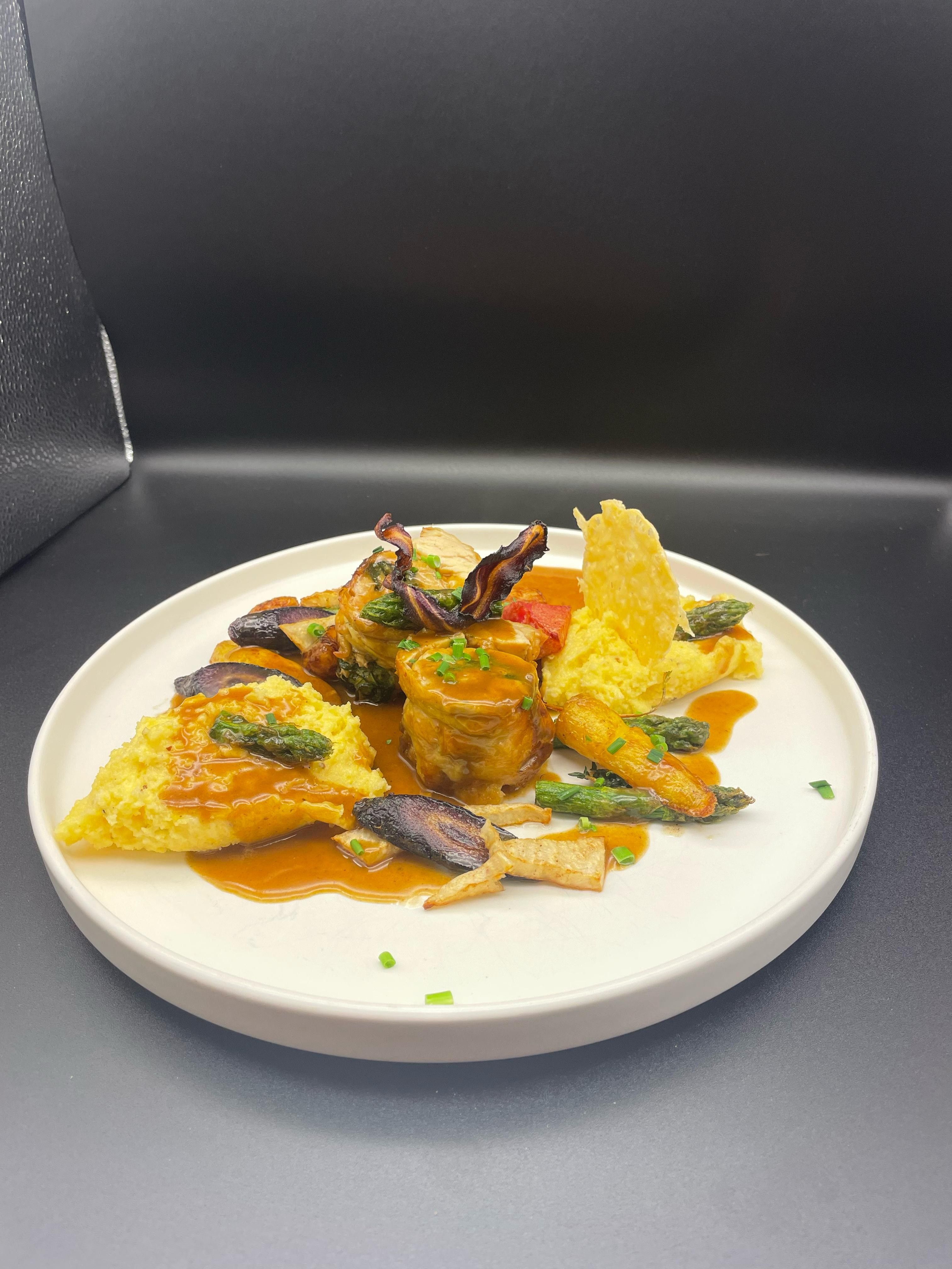 Gourmetgericht auf weißem Teller mit Fleisch, Gemüse und Sauce.