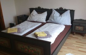 Ein traditionell dekoriertes Doppelbett mit zwei Nachttischen in einem Schlafzimmer.