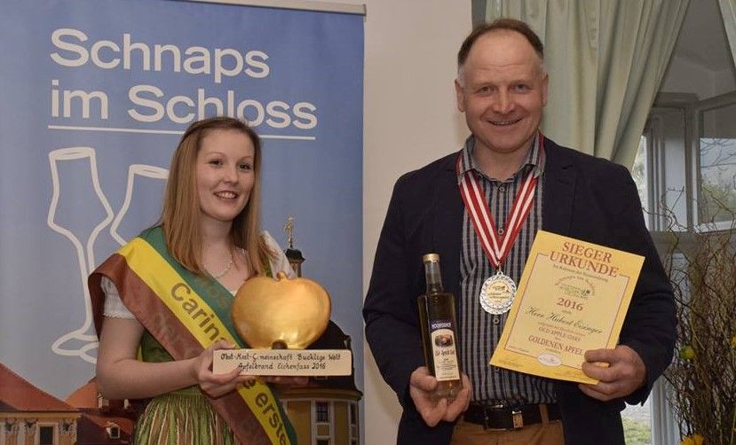 Zwei Personen halten eine Trophäe und eine Urkunde bei einer Preisverleihung.