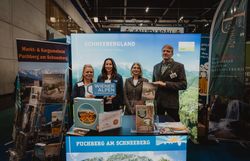 Vier Personen mit dem Schild Wiener Alpen in Niederösterreich vor dem Stand Schneebergland