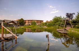 Naturhotel Molzbachhof mit Teich und Liegestühlen im Vordergrund.