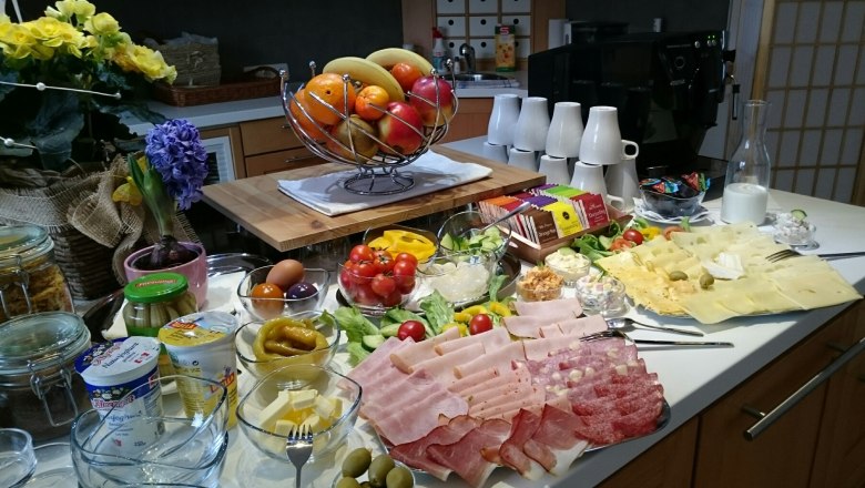Ein reichhaltiges Frühstücksbuffet mit Aufschnitt, Käse, Obst, Gemüse und Joghurt.