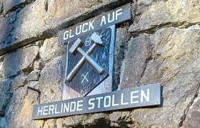 Eingang zum Herlinde Stollen mit Bergbauzeichen und Schriftzug 'Glück Auf'.