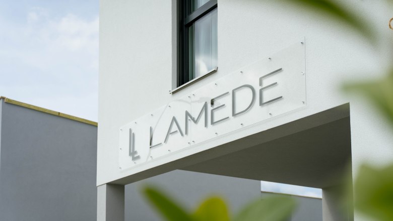 Aussenansicht, © Hotel Lamede Moderne Gebäudeaußenansicht mit dem Schriftzug 'LAMEDE' auf einem Schild.