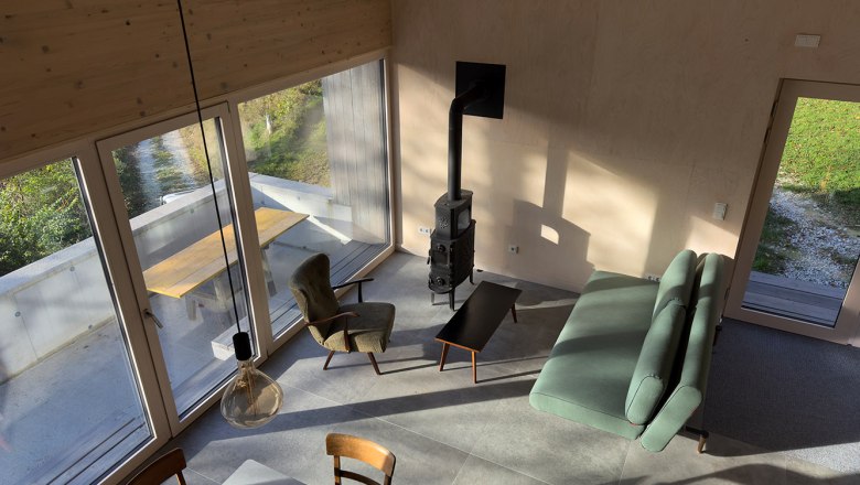 Moderner Wohn- und Essbereich mit großen Fenstern, Sofa, Sessel und Kamin.