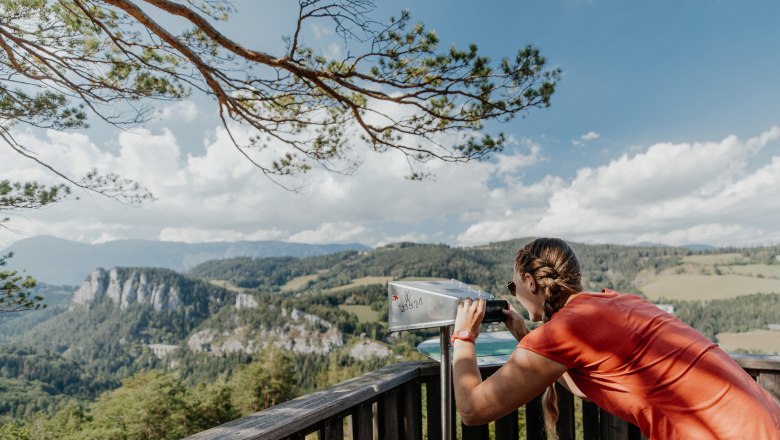 Frau schaut durch emen viewer auf eine Berglandschaft am Semmering Bahnwanderweg.