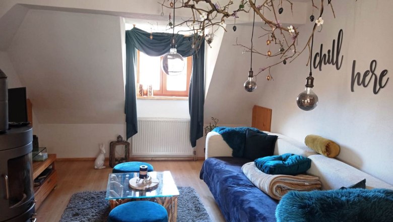Cozy living room with sofa, blue carpet, decorative branches and 'chill here' lettering.