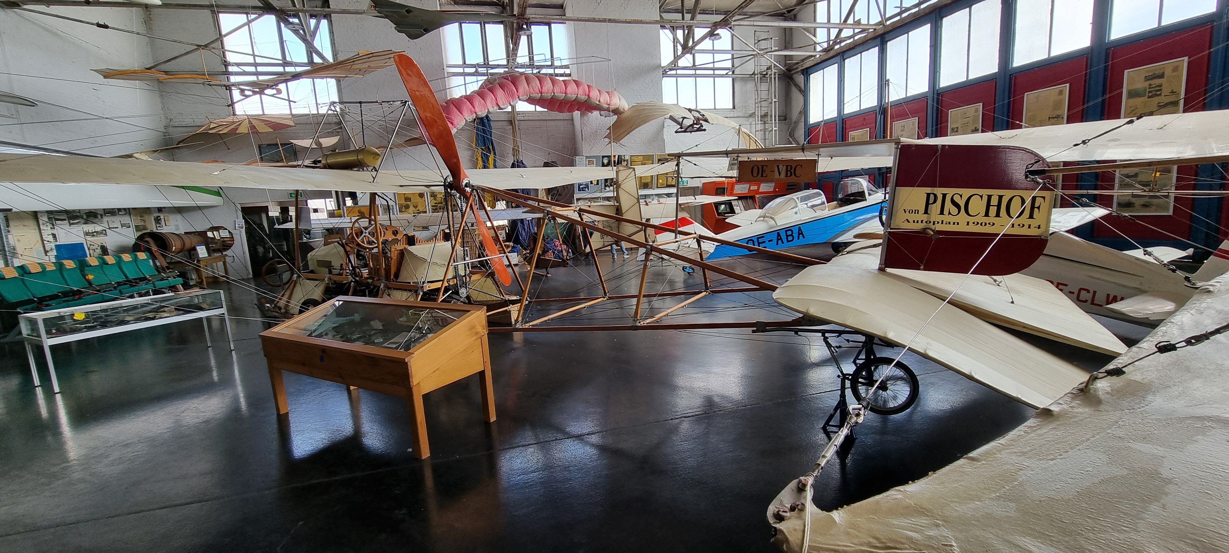 Große Halle mit Flugzeugen am Boden und vom Dach hängend