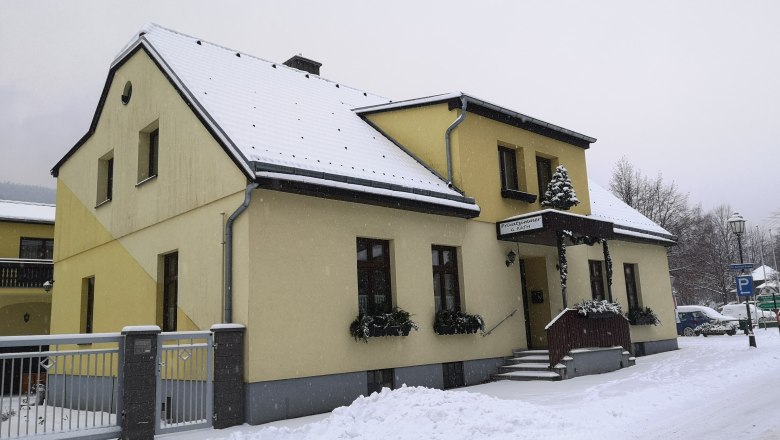 Yellow house in the snow with snow-covered roof and sidewalk.