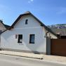 A small, white vacation home with a brown gate and a mountain backdrop.