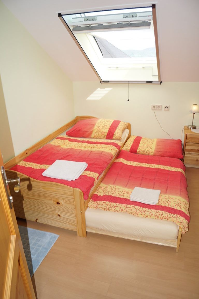 Einzelzimmer mit zwei Betten unter einem Dachfenster.