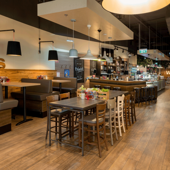 Innenansicht eines modernen Cafés mit Holzmöbeln und Hängelampen.