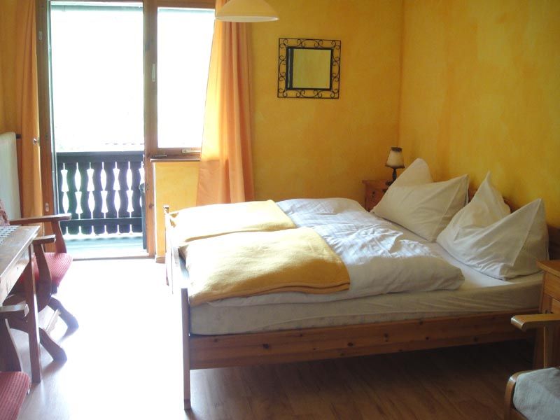 Gemütliches Zimmer mit Holzmöbeln, gelben Wänden und Balkon.