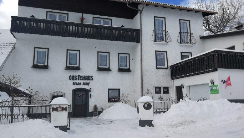 Winterliche Ansicht eines Gästehauses mit Schnee bedeckt.