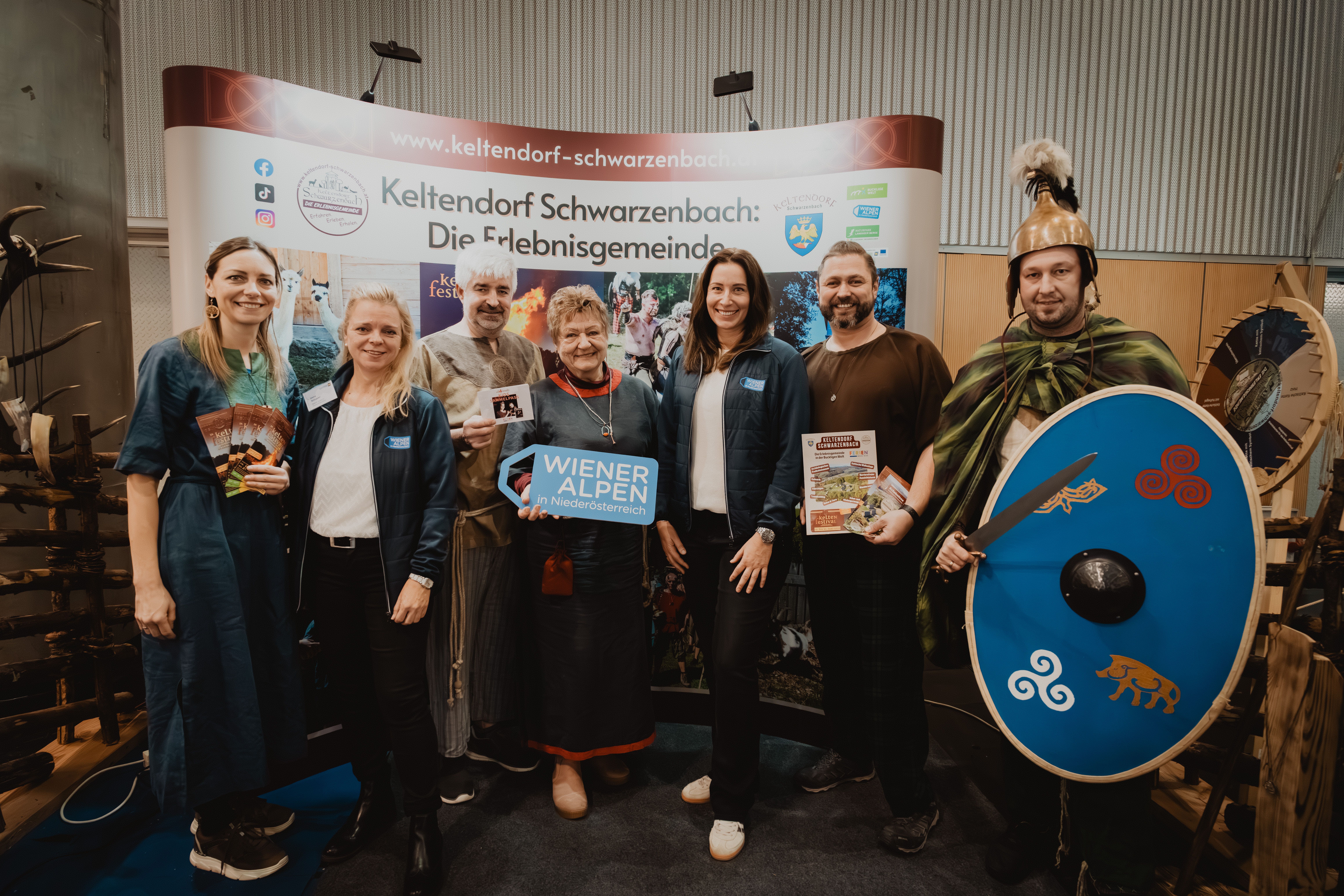 Sieben Personen mit dem Schild Wiener Alpen in Niederösterreich vor dem Stand Keltendorf Schwarzenbach