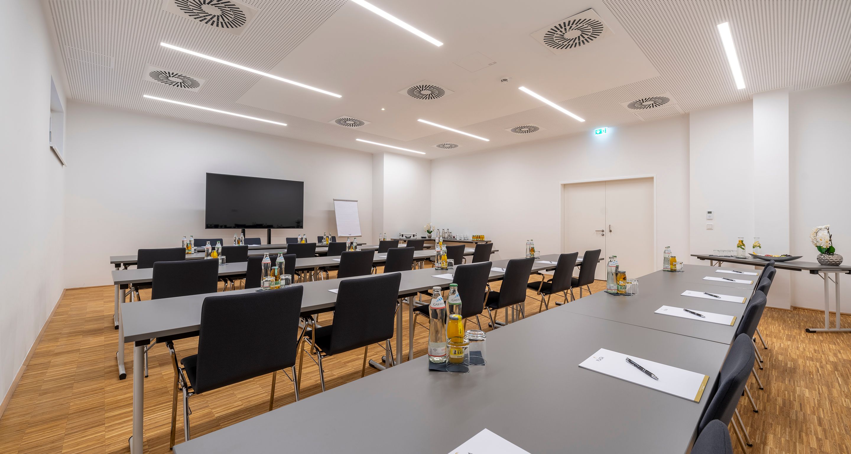 Großer, heller Seminarraum mit Fernseher, Tischen und Bestuhlung