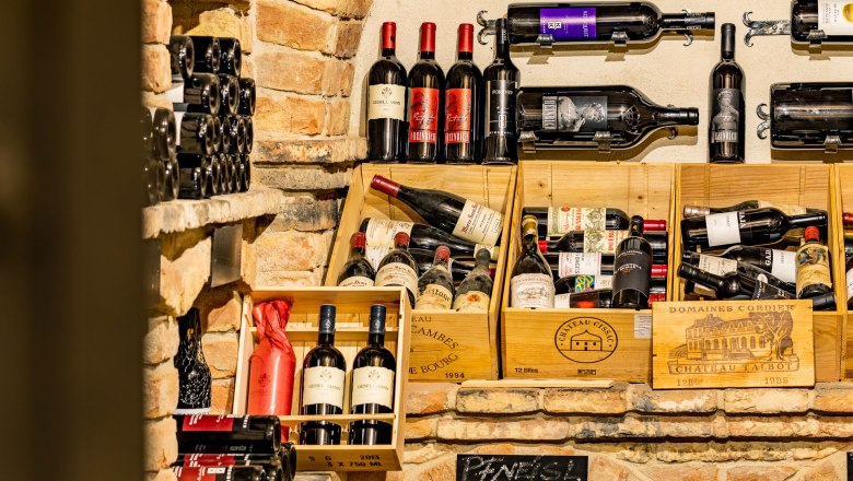 Weinflaschen in einem rustikalen Weinkeller mit Backsteinw&auml;nden.