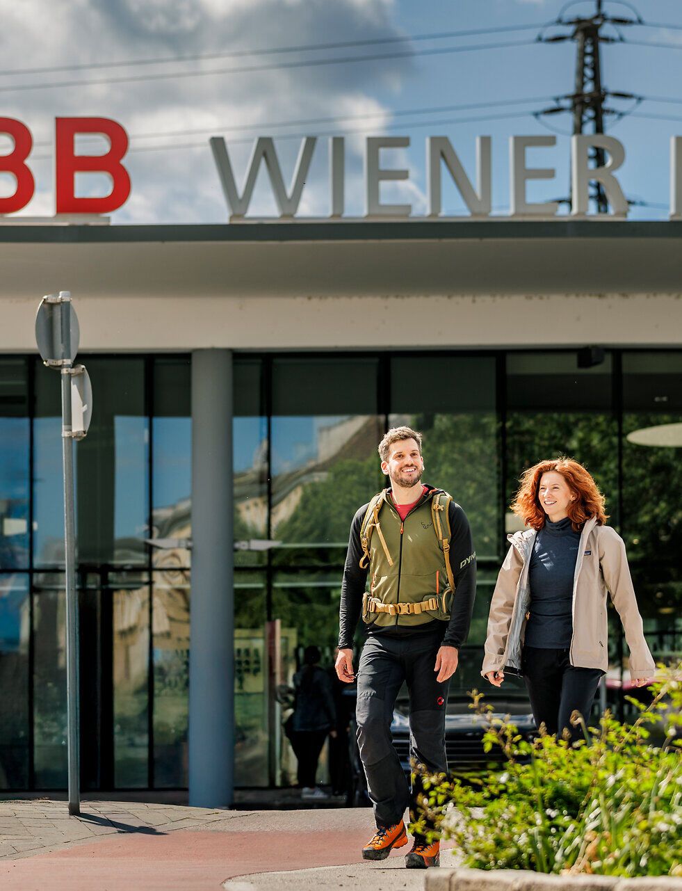 Ein Frau und ein Mann gehen vor dem Bahnhof Wiener Neustadt.