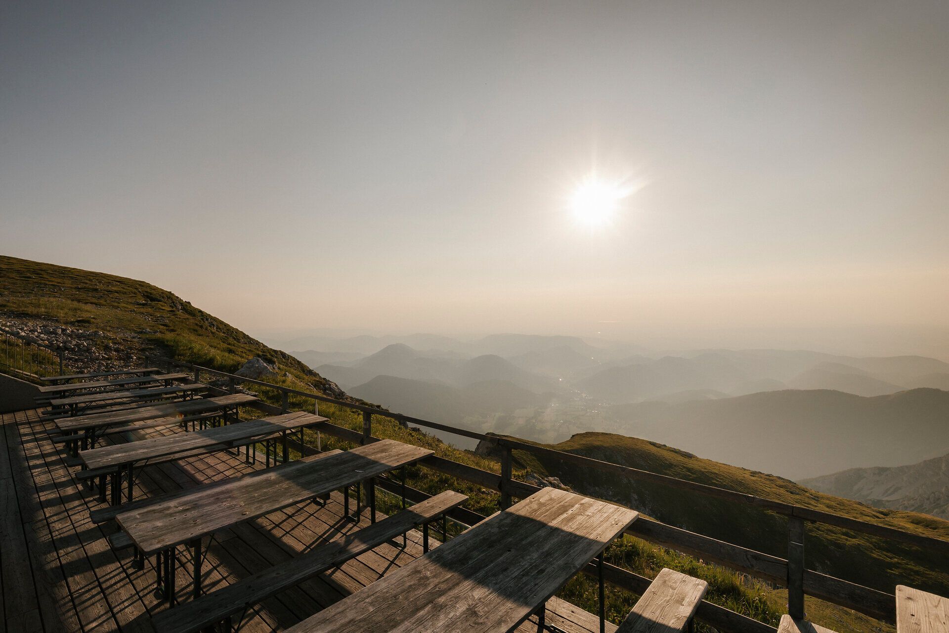 Sonnenterrasse der Fischerhütte am Schneeberg mit Holztischen und weitem Blick über die Berglandschaft