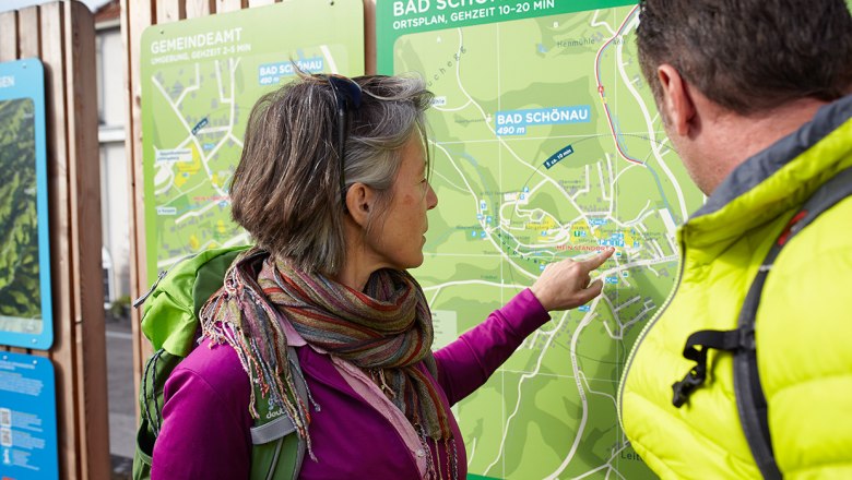 Two people look at a hiking map of Bad Sch&ouml;nau.