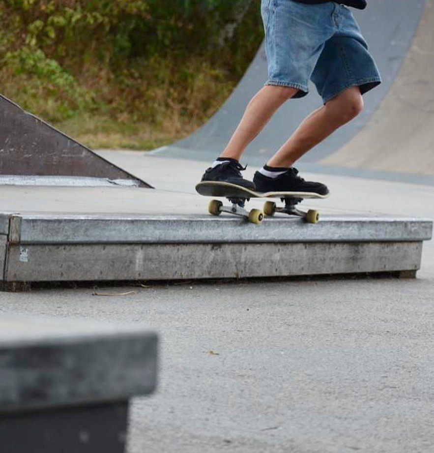 Person übt Skateboard-Trick auf einer Rampe im Skatepark.