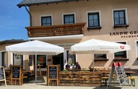 Outdoor area of a restaurant with parasols and blackboards with food offers.