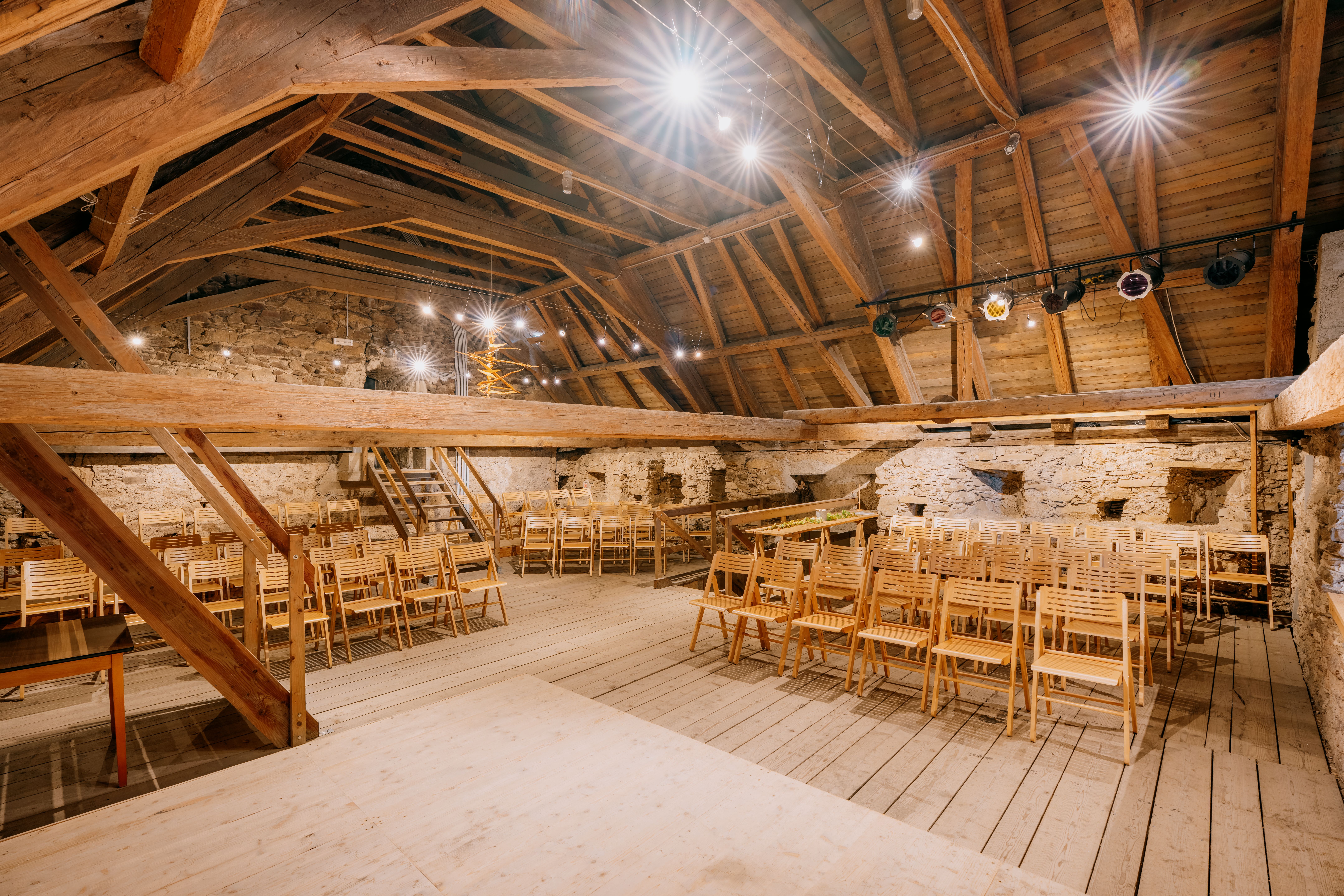 Ein Dachstuhl in einer Wehrkirche aus einer aufwendigen Holzkonstruktion, fotografiert von der Bühne aus sieht man das Holzgewölbe, Holzstuhle und Holzbalken, sowie die Lichttechnik.