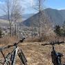 Two bicycles in front of a mountain landscape with a view of a valley and a town.