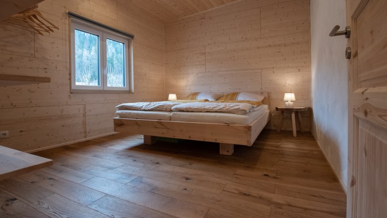Holzverkleidetes Schlafzimmer mit Doppelbett und Nachttischlampen.