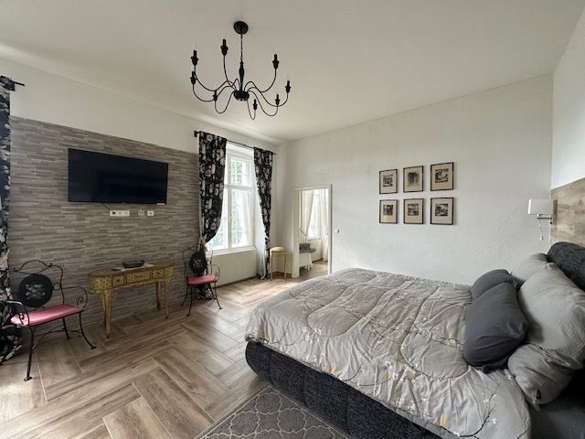 Elegantes Hotelzimmer mit großem Bett, Kronleuchter, Fernseher und dekorativen Elementen.